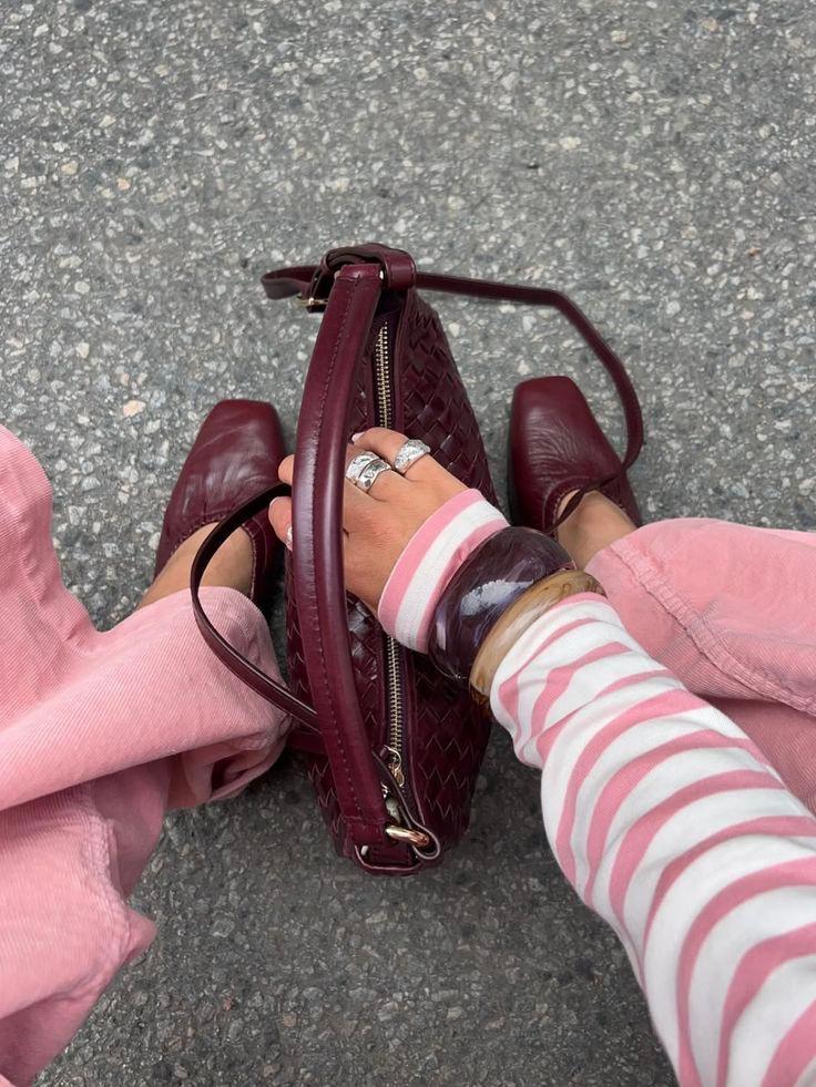 Pink outfit styled with a deep burgundy woven bag and burgundy shoes