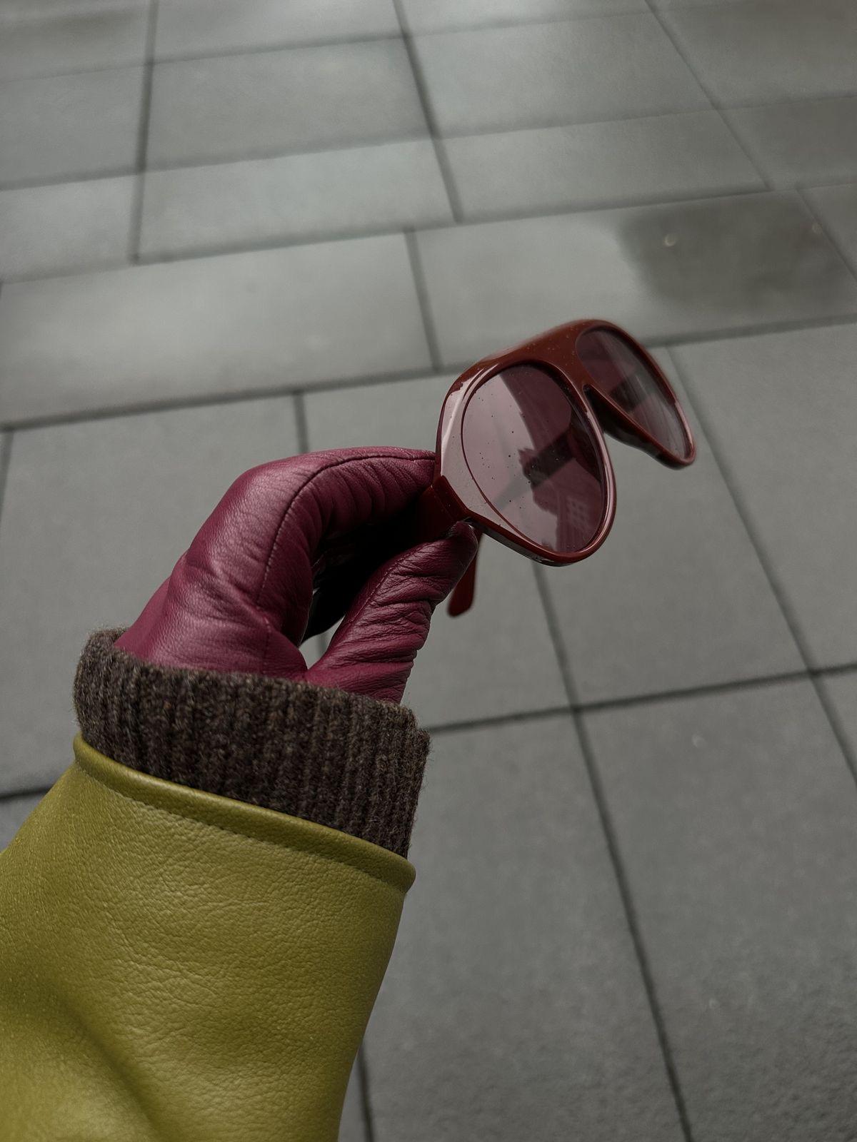 Olive green leather sleeve styled with burgundy leather gloves and burgundy sunglasses