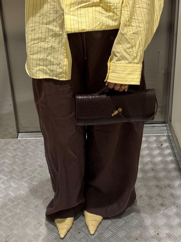 Chocolate brown wide-leg trousers styled with a butter yellow striped shirt and matching yellow shoes